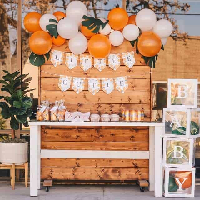 an orange and white dessert bar with balloons on it's top, along with photos