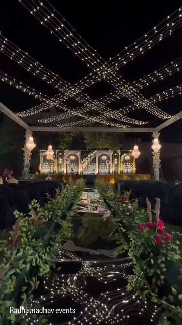 an outdoor event with lots of lights on the ceiling and flowers in the foreground