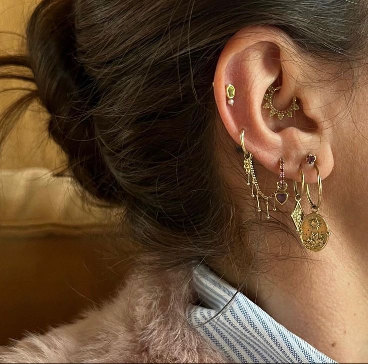 a close up of a person wearing ear rings and earrings with charms on their ears