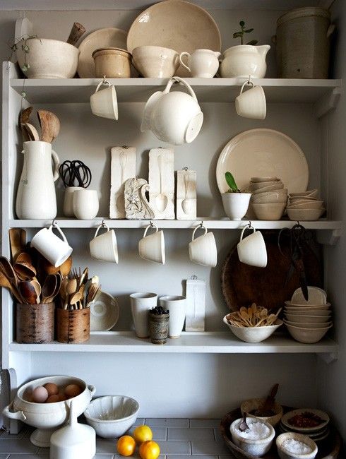 the shelves are filled with white dishes and bowls, cups, and utensils