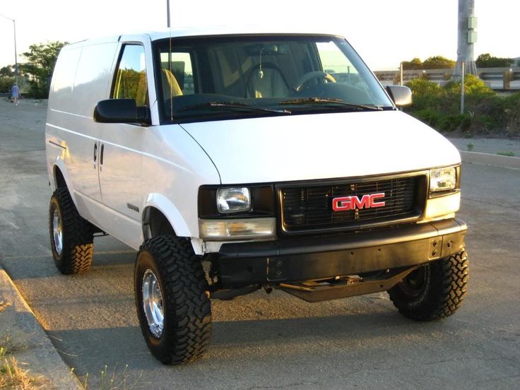 a white gmc van is parked on the street