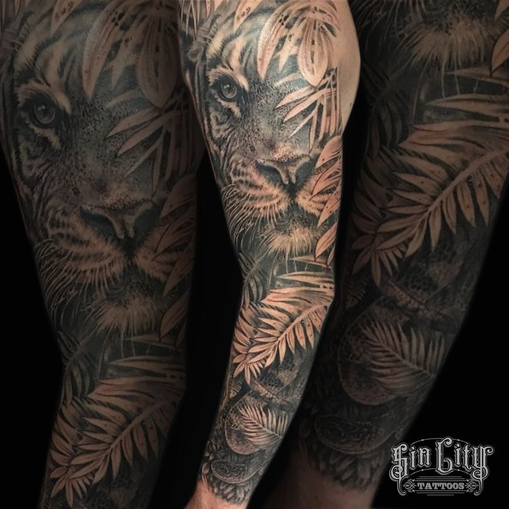 a man's leg with tattoos on it and an image of a tiger in the background