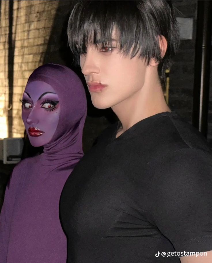 a woman with black hair and purple makeup is standing next to a mannequin