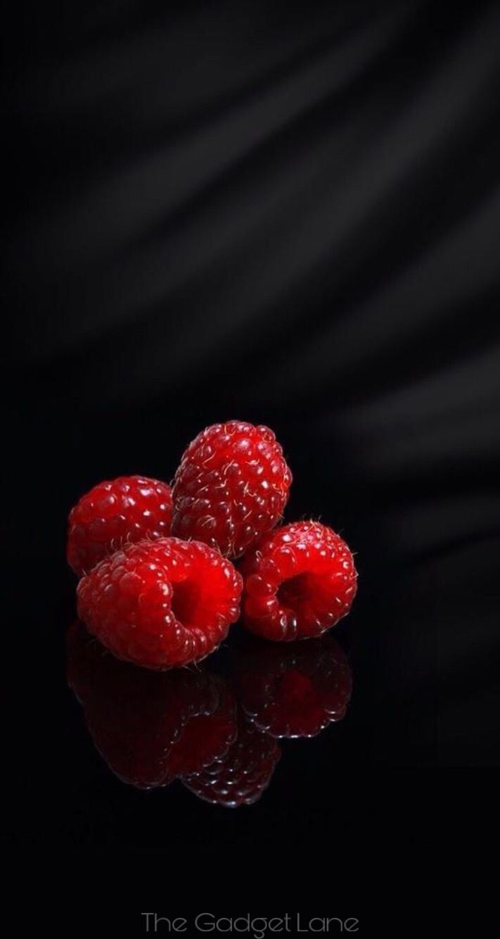 some raspberries are sitting on a black surface