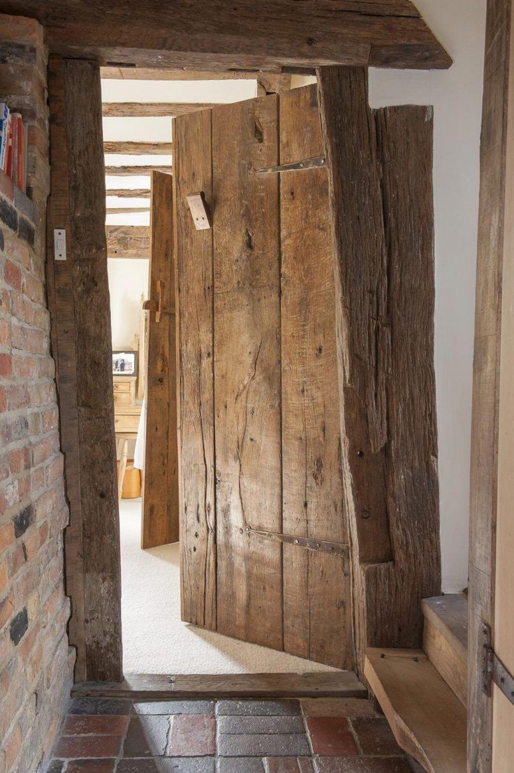 an open door leading into a room with brick flooring and exposed beams on the walls