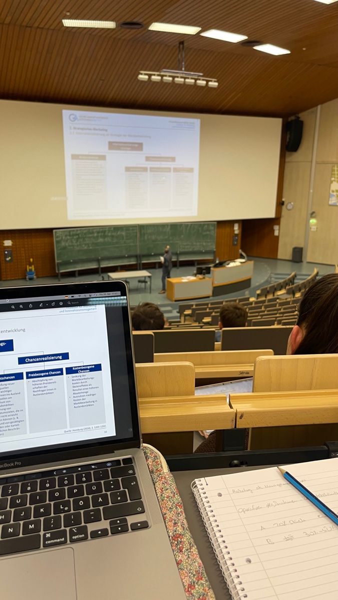 an open laptop computer sitting on top of a desk in front of a class room