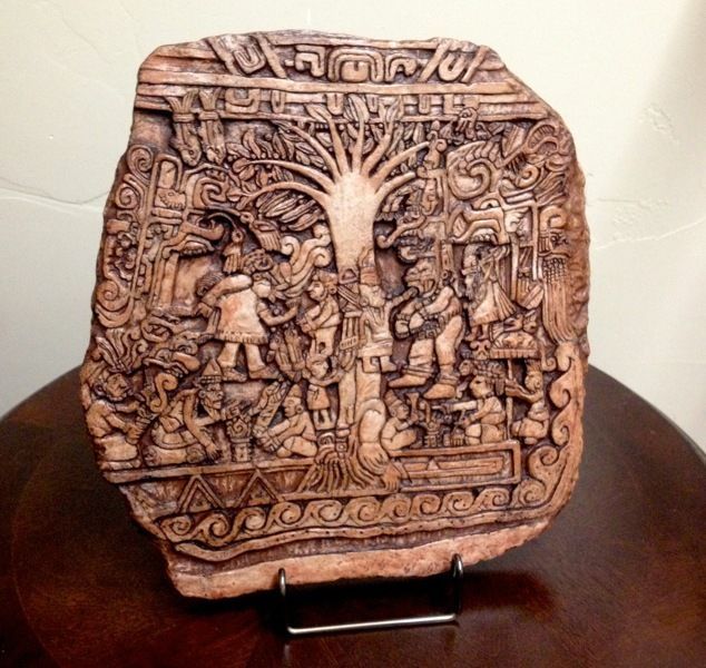 an intricately carved wooden block with people and animals on it, sitting on top of a table