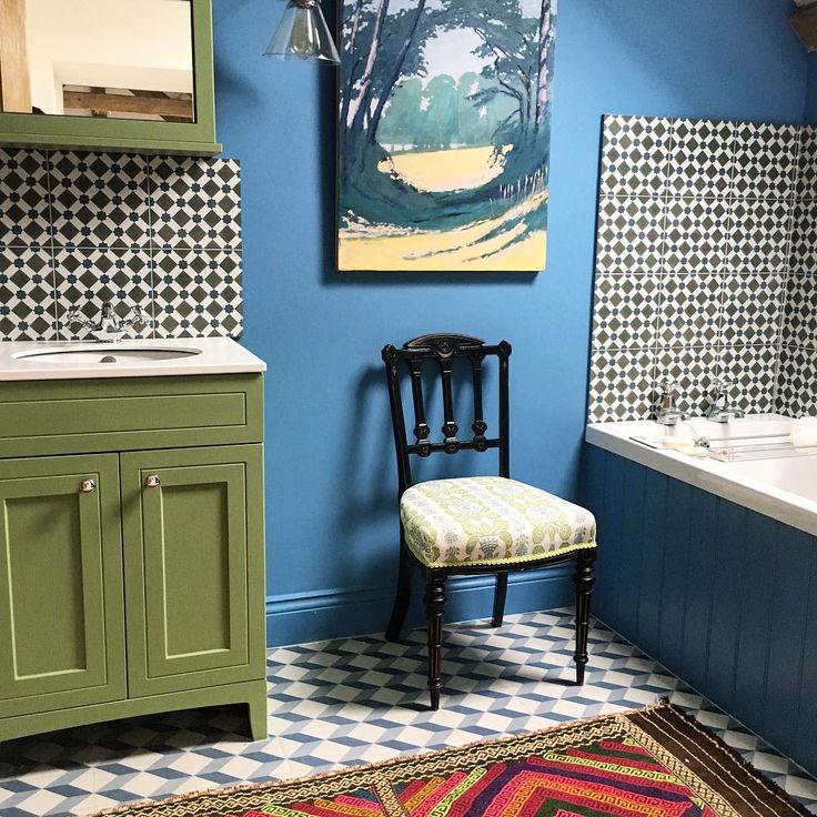 a bathroom with blue walls, green cabinets and a patterned rug on the floor next to a bathtub