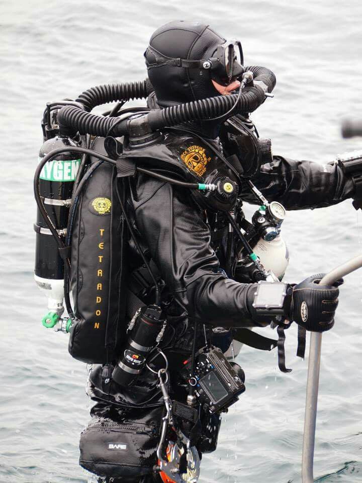 a man in scuba gear standing on the side of a boat holding onto a railing