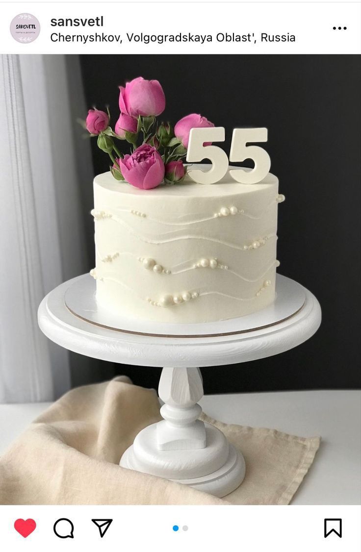 a white cake sitting on top of a table next to a napkin and pink flowers