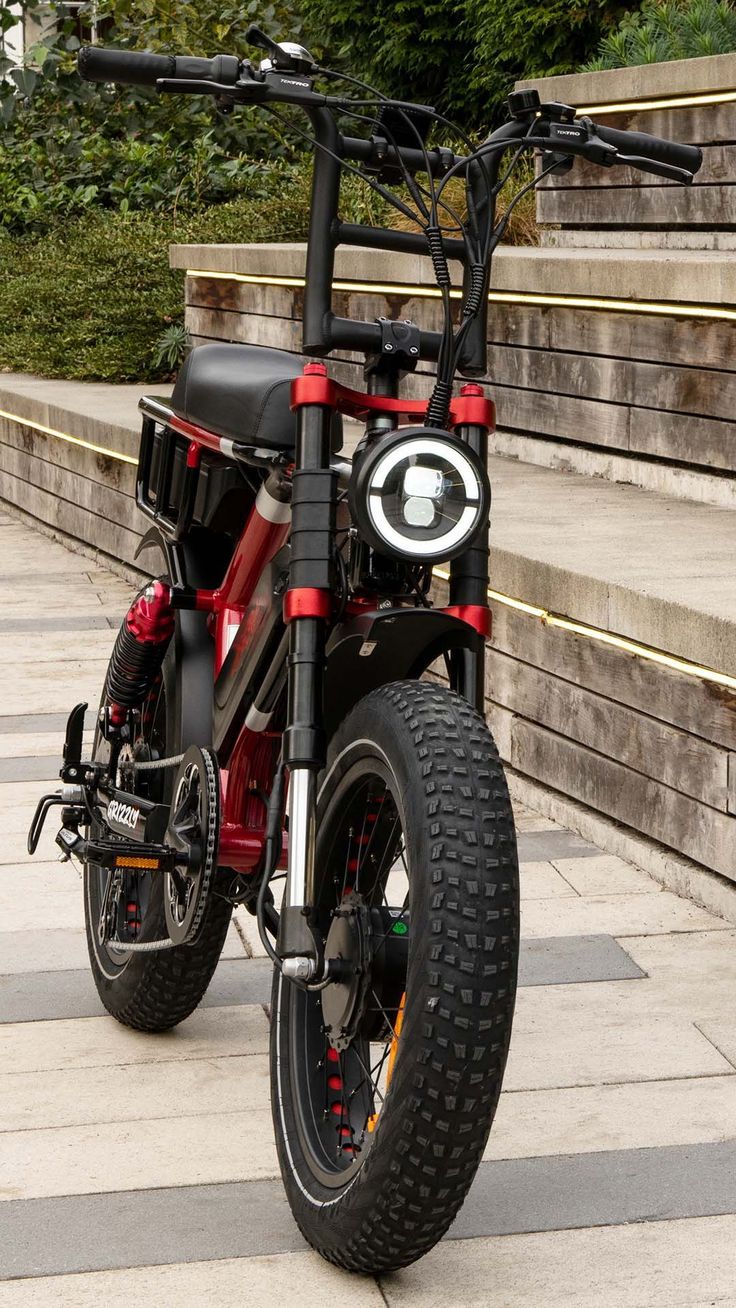 a red and black bike parked on the side of a street next to some steps