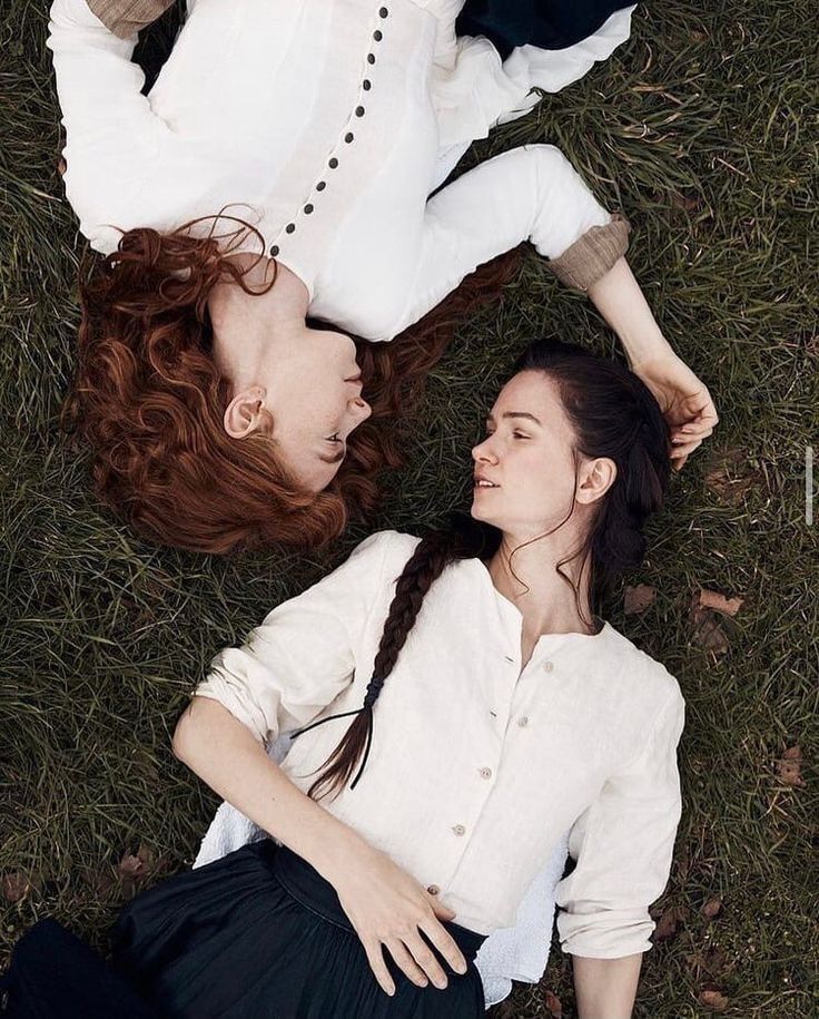 two young women laying on the grass together