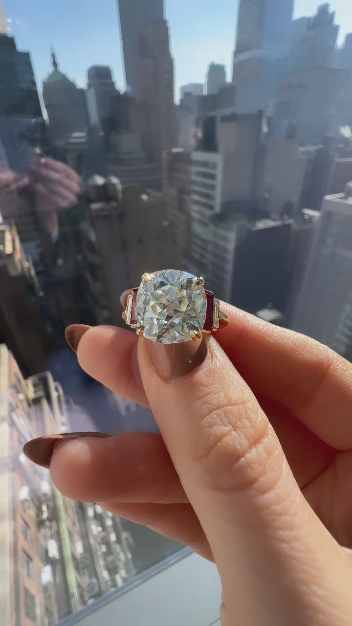 a woman's hand holding an engagement ring in front of a cityscape