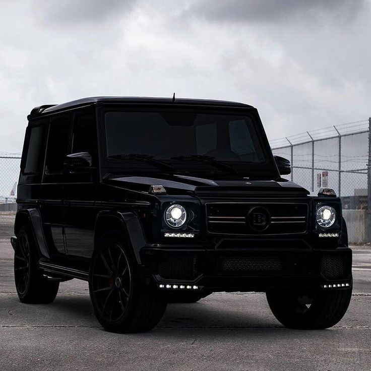 a black mercedes g - class parked in front of a fence