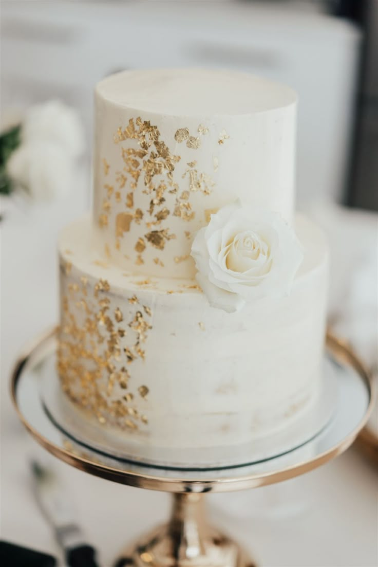 a white and gold wedding cake sitting on top of a table