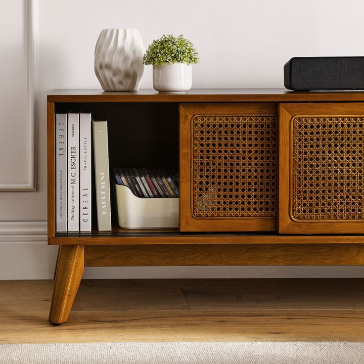 a wooden cabinet with books and plants on top