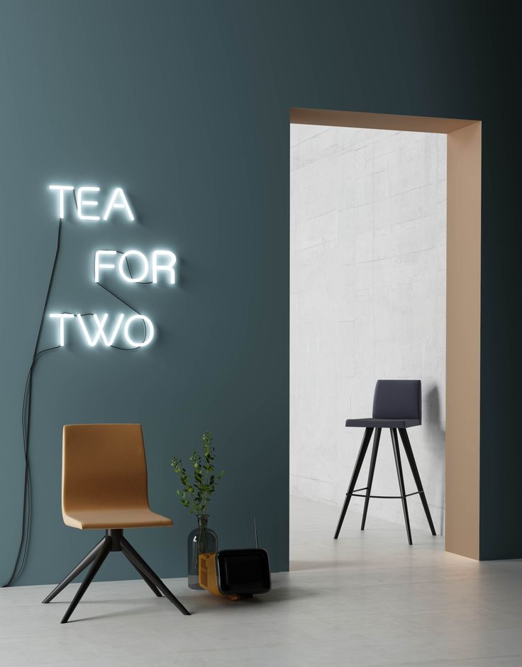 a chair and table in a room with a neon sign on the wall above it that says tea for two