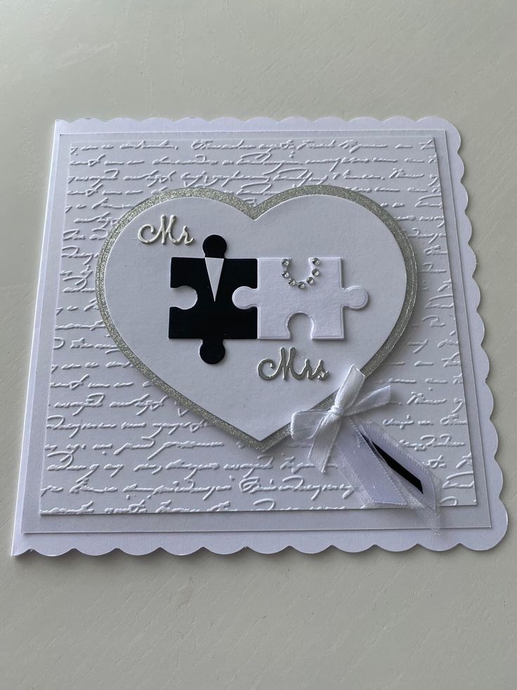 a white card with two pieces of puzzle in the shape of a heart on it