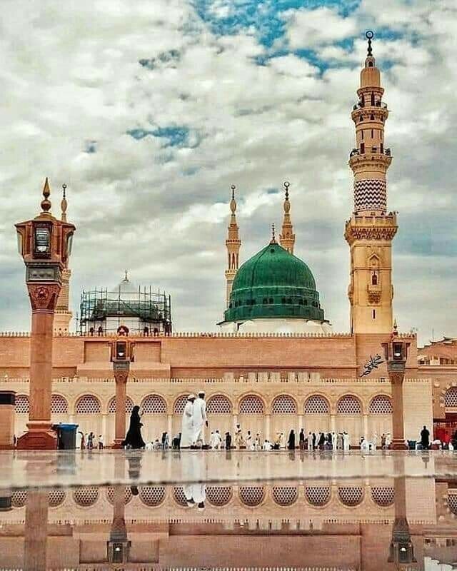 people are walking around in front of a building with a green dome on the top