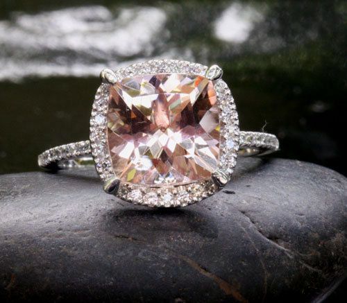 an engagement ring with a fancy cushion cut diamond surrounded by pave diamonds on a rock