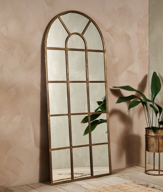 a large mirror sitting next to a potted plant