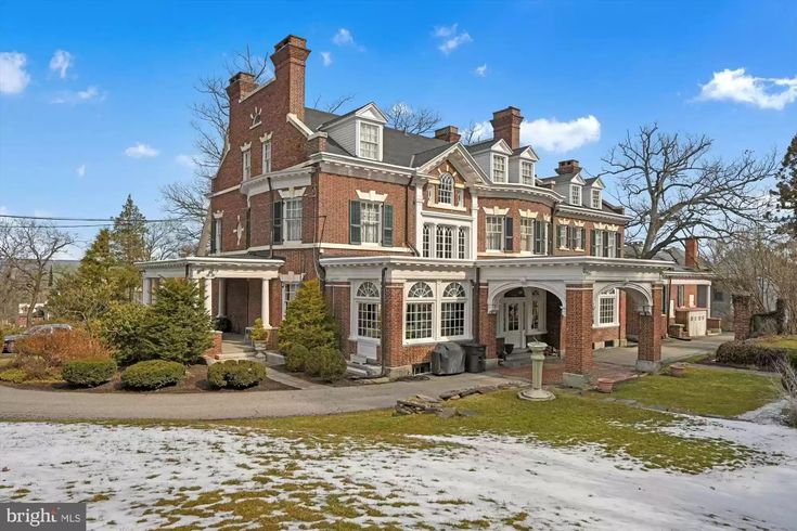 a large brick house with many windows and lots of snow on the ground in front of it