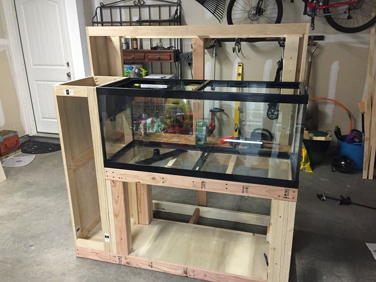 a large fish tank sitting on top of a wooden stand in a garage next to a bike