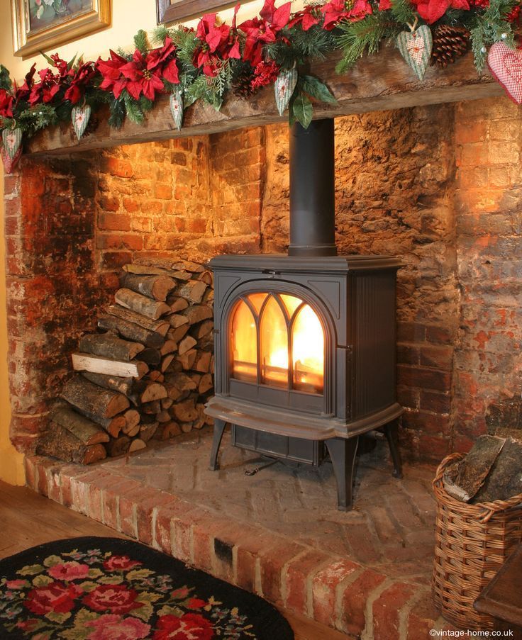 a wood burning stove sitting inside of a living room next to a pile of logs