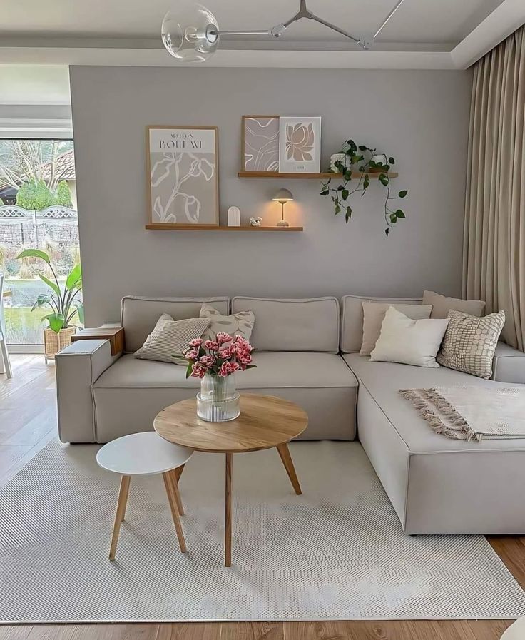 a living room filled with furniture and flowers on top of a coffee table in front of a window