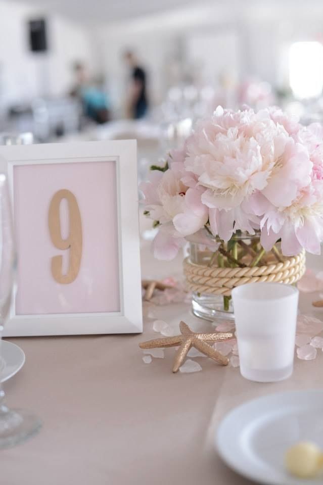 the table is set with pink flowers and place settings for guests to sit down at