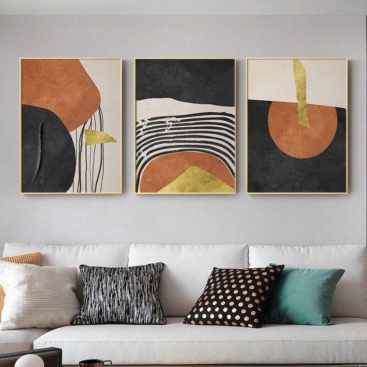 two abstract paintings hang on the wall above a white couch in a modern living room