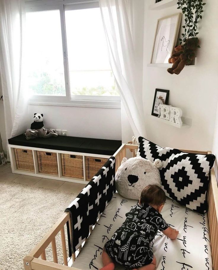 a small child laying in a wooden crib next to a window