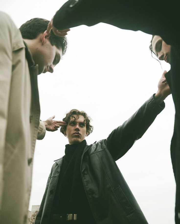 three men standing around each other with their hands together