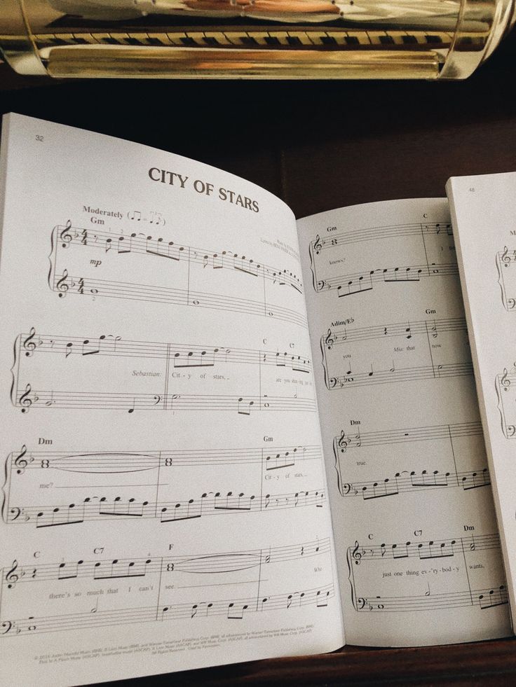 an open book with sheet music in it on top of a table next to a piano