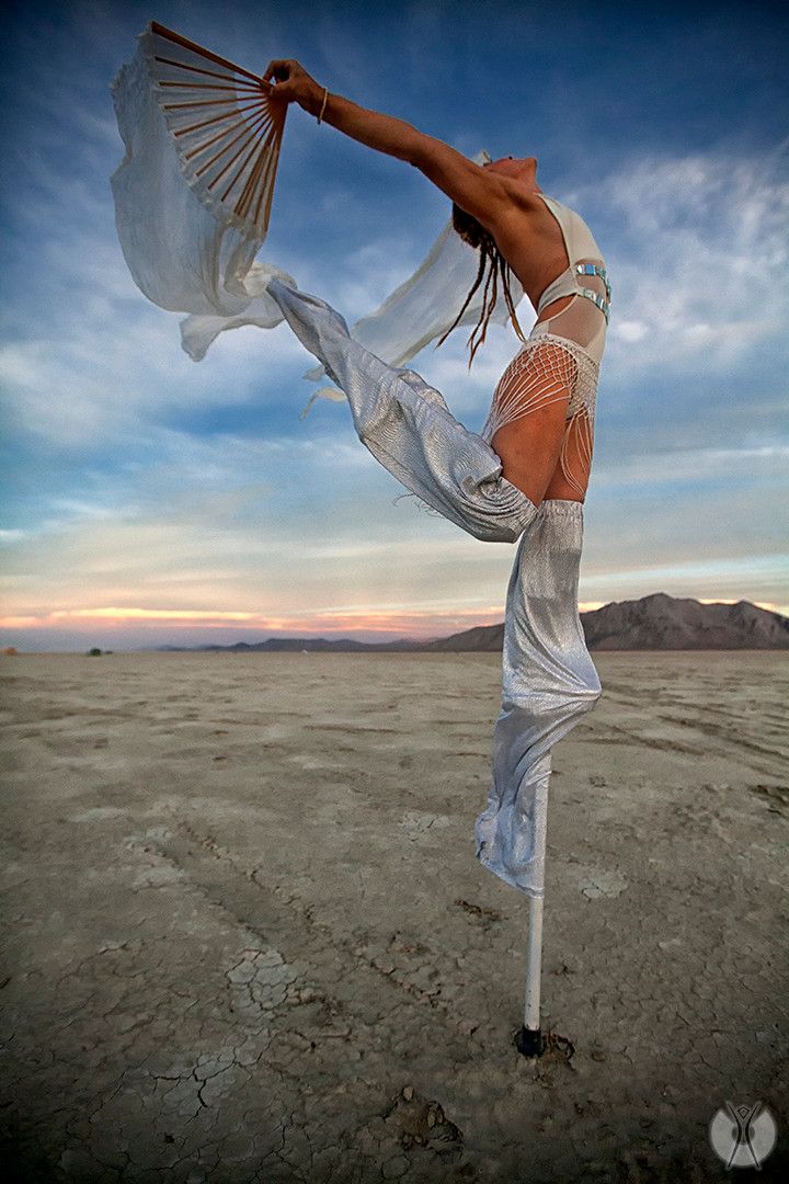 a woman is dancing in the desert with her arms stretched out