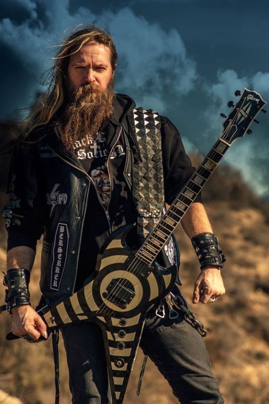 a man with long hair and beard holding an electric guitar