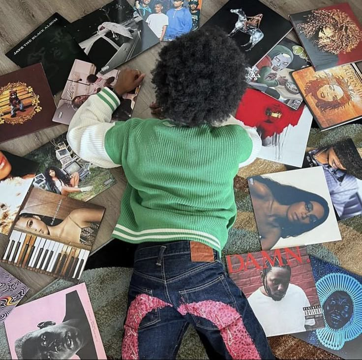 a woman laying on the floor surrounded by various records and cds, with her back to the camera