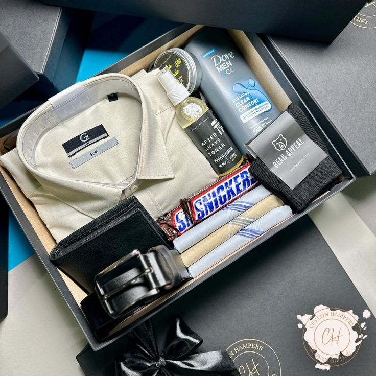 an open box containing men's personal care items and a tie on the table