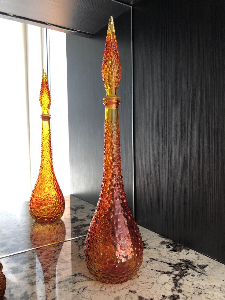 two glass vases sitting on top of a marble counter