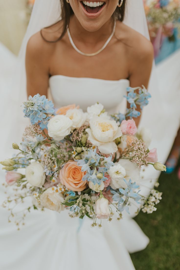 a woman in a white dress holding a bouquet of flowers and smiling at the camera