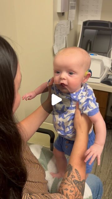 a woman holding a baby up to her face while sitting in a hospital bed with an arm tattoo on it