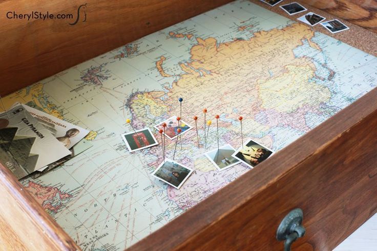 an old wooden chest with pictures and photos on the lid, in front of a map