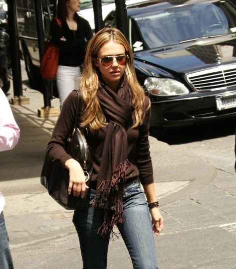 a woman is walking down the street with her hand in her pocket and wearing sunglasses