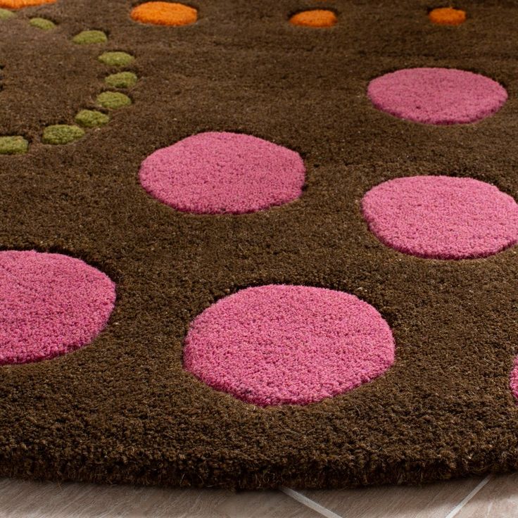 a brown rug with pink and green polka dots on the bottom is sitting on a tile floor