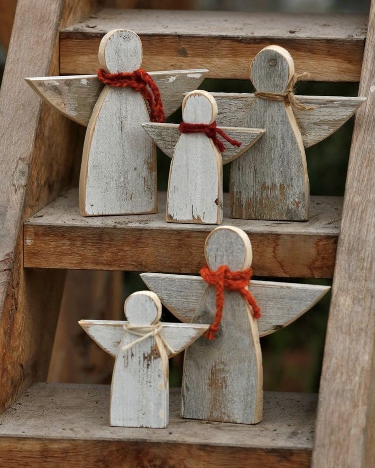 three wooden angel figurines sitting on top of a set of steps with red ribbon