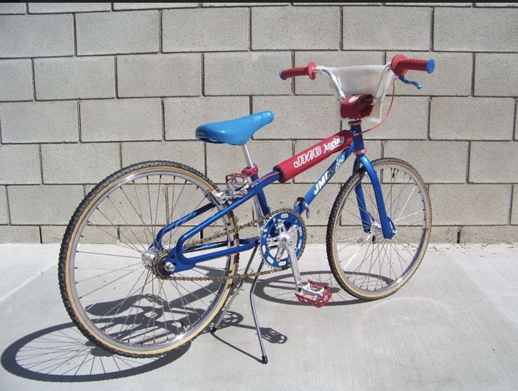 a blue and red bicycle parked next to a brick wall