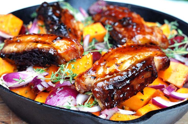 a pan filled with meat and vegetables on top of a wooden table