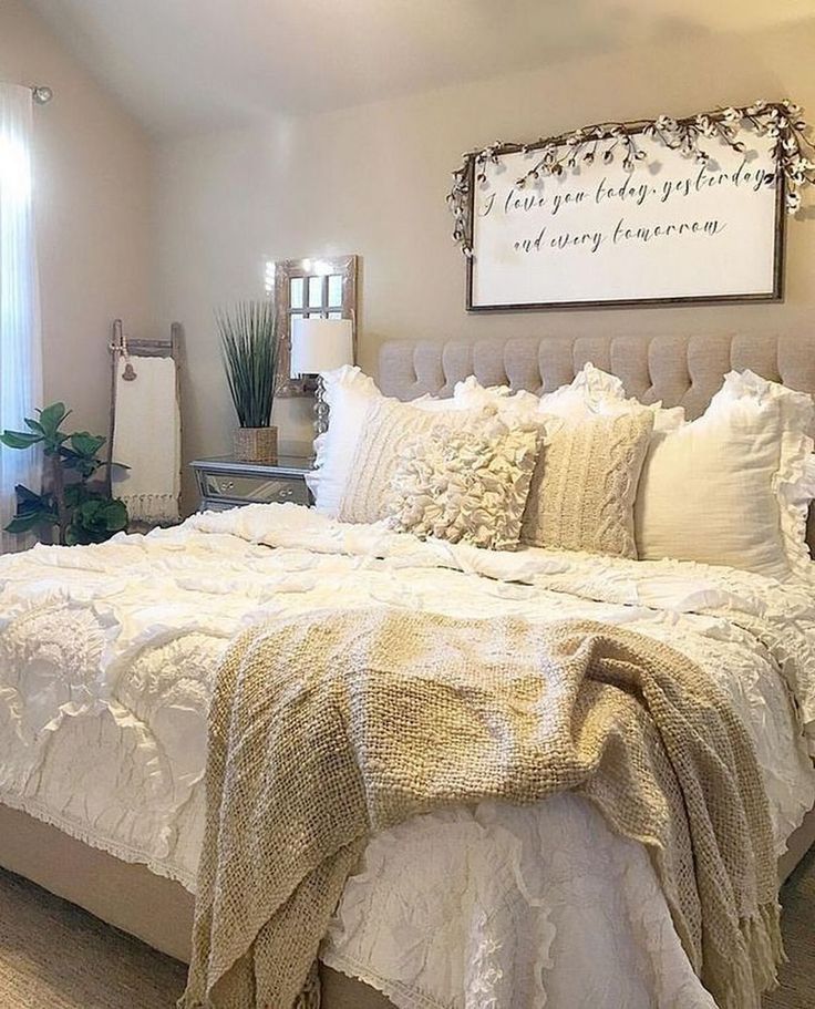 a white bed sitting in a bedroom next to a window covered in blankets and pillows