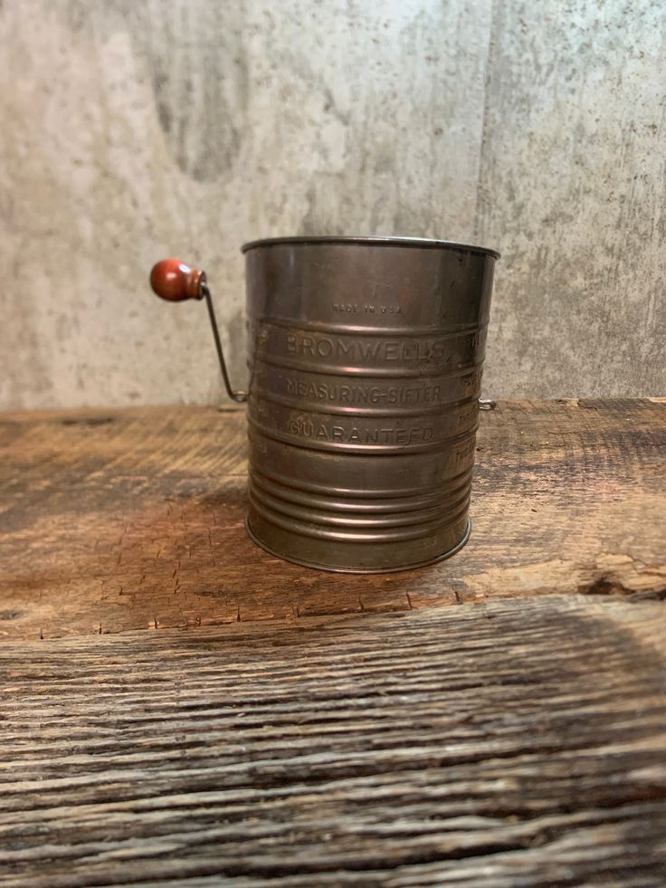 a metal cup sitting on top of a wooden table