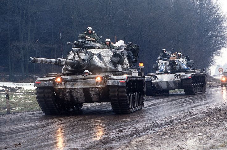 tanks driving down a road in the rain